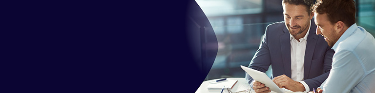 Két profi szakember ül együtt egy asztalnál egy világos irodai környezetben, egy dokumentumot vagy táblagépet áttekintve egy üzleti megbeszélés során.